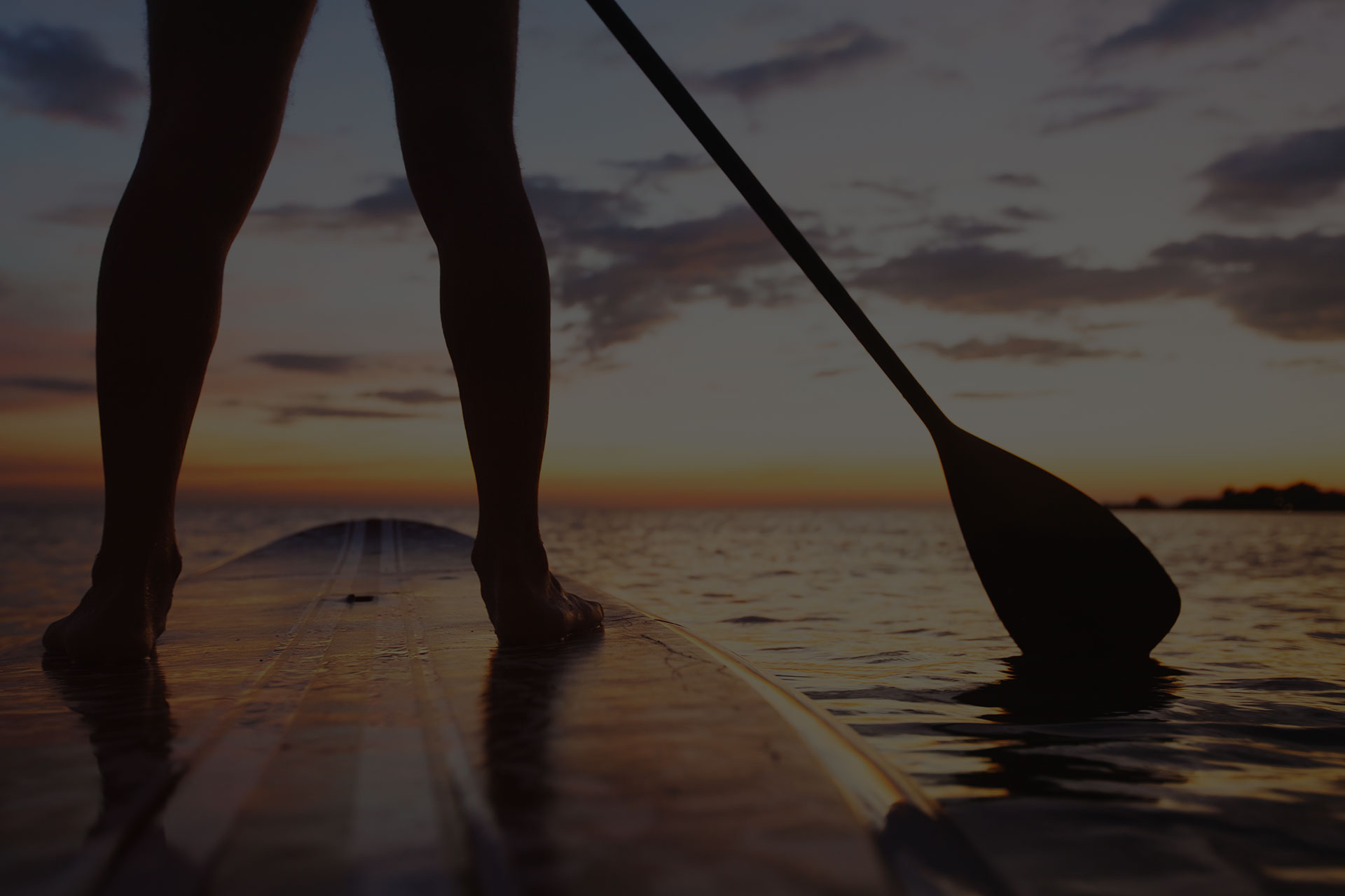 Stand up paddle boarding on a quiet sea with warm summer sunset colors